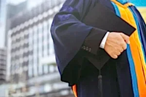 Akademik cübbe giymiş kişi elinde mezuniyet kepi tutuyor – 2025 Mart ve Ekim doçentlik başvuru kriterleri ve ÜAK şartları.
