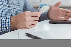 Belgeler ve Türk lirası banknotları tutan kişi – 2025 doçentlik başvurusu ücreti, evrak süreci ve ödeme yöntemleri.