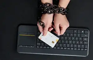 Klavye üzerinde zincirlenmiş eller ve kredi kartı – TCK 157-158 kapsamındaki bilişim yoluyla dolandırıcılık suçları ve ceza süreçleri.