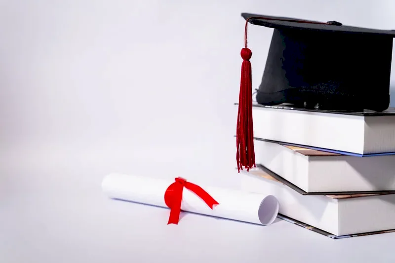 Kitap yığını üzerindeki mezuniyet kepi ve kırmızı kurdeleli diploma – yurt dışı denklik başvurusu ve STS sınavı iptal davası.