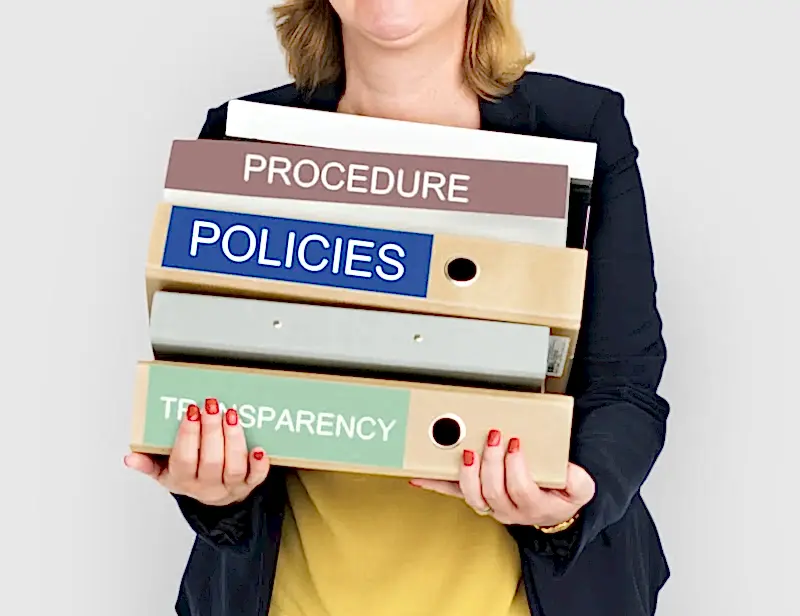 Bir profesyonelin elinde "PROCEDURE", "POLICIES" ve "TRANSPARENCY" etiketli dosya klasörlerini tuttuğu, kurumsal yönetim ve hukuki uyum süreçlerini temsil eden görsel.