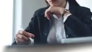 Profesyonel bir takım elbise giymiş bir hukukçunun veya danışmanın elinde stylus kalemle belge veya tableti incelediği, derinlemesine düşünce anını gösteren yakın çekim.