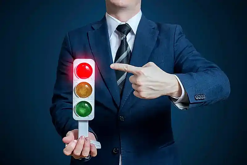 Kırmızı ışığı gösteren takım elbiseli kişi – hukuka aykırı trafik cezalarına itiraz süreci ve avukat desteği.