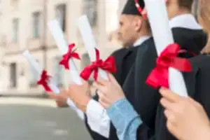 Sıraya dizilmiş 3 yeni mezun ellerinde diploma tutuyor.